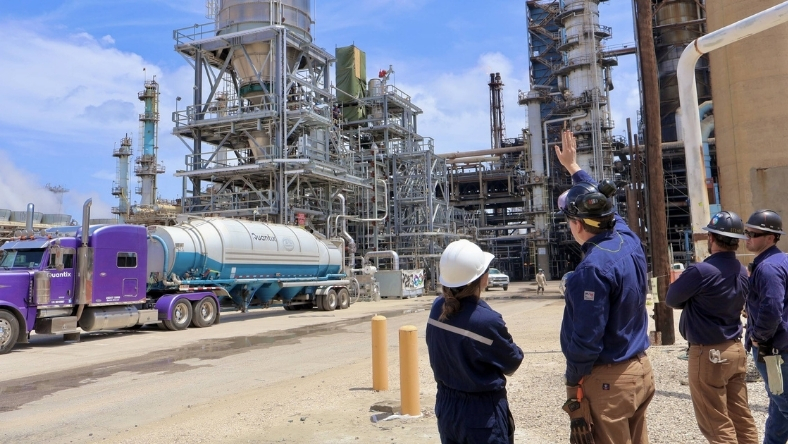 Engineers inspecting large industrial chemical processing facility with tanker truck