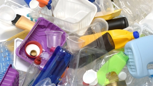 Pile of mixed plastic waste including bottles, containers, trays, and packaging items in various colors