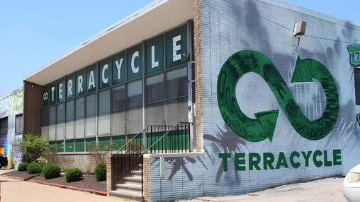 TerraCycle office building with bold green and white signage and a large infinity loop mural on the side wall