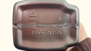 Hand holding a dark plastic tray showing the HDPE recycling symbol and Made in USA stamp on the base
