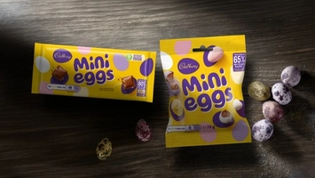 Yellow snack packaging on a dark wooden surface with small speckled sugar-coated eggs scattered to the right