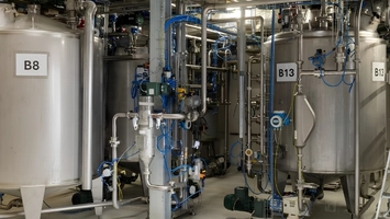Stainless steel tanks B8 and B13 linked by blue piping inside an industrial bioplastics production facility
